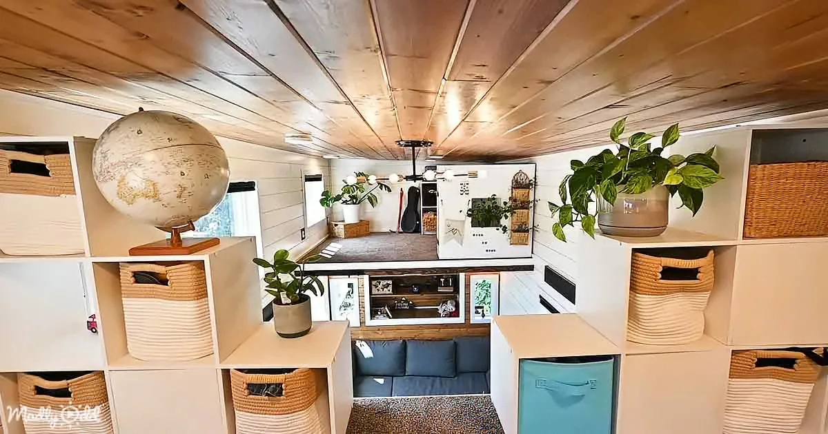 A cozy, organized tiny home interior with shelves, plants, and a globe on top of a storage unit.