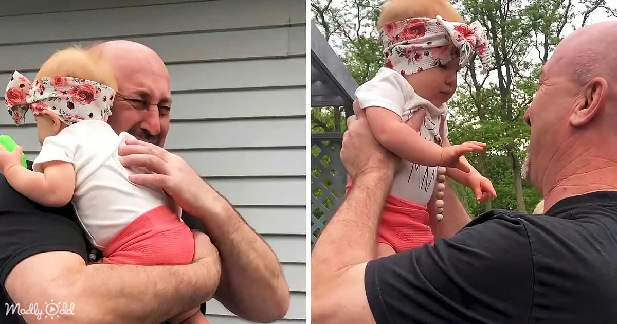 A man holds a baby wearing a floral headband, both smiling and enjoying each other's company.