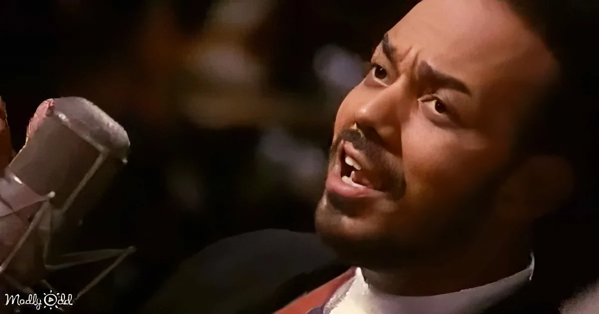 A man in a suit sings into a microphone, his eyes closed, in a dimly lit setting.