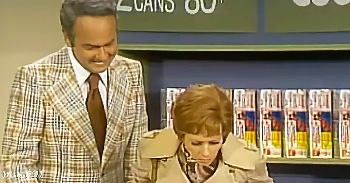 A man in a plaid suit stands beside a woman in a trench coat, both in a store setting with magazines in the background.