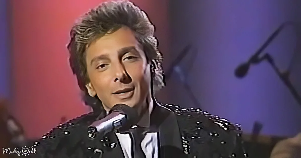 A person with styled hair and a sequined jacket sings into a microphone against a red and purple background.