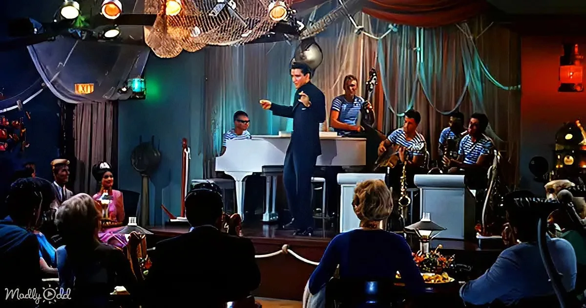 A man in a suit leads a jazz band on stage in a dimly lit, elegant venue.