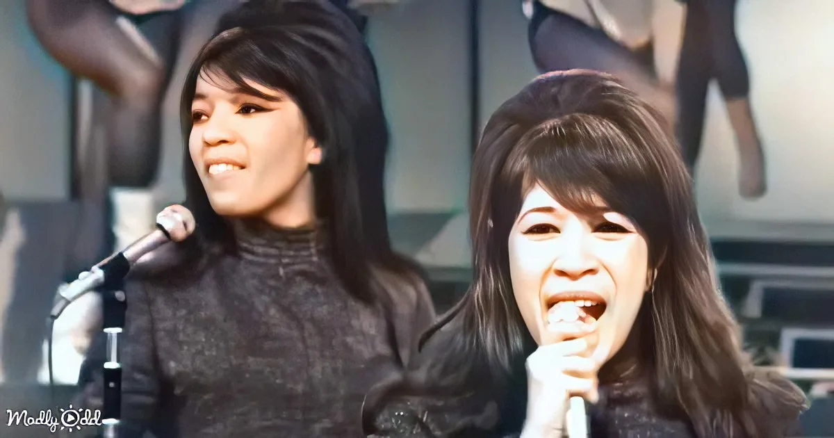 Two women sing into microphones, one with long dark hair, the other with bangs, both smiling.
