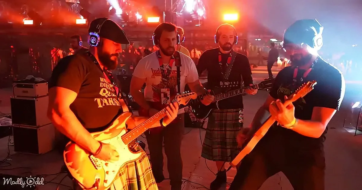 A band in kilts plays guitars under vibrant red stage lights.