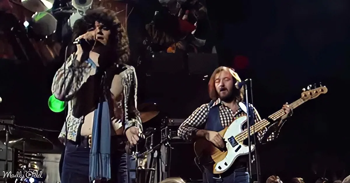 A musician sings passionately while another plays bass guitar on stage.