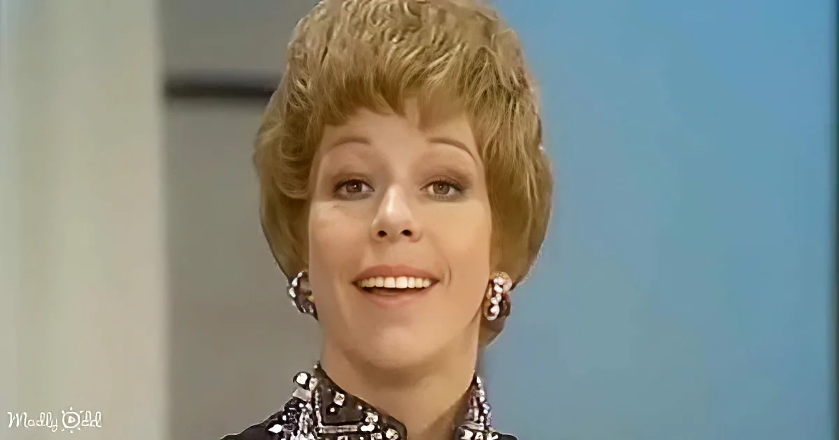 A woman with short, styled blonde hair and earrings smiles in a studio setting.