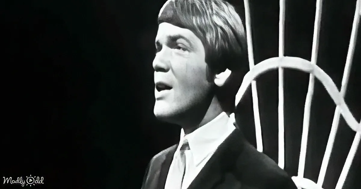A man in a suit and tie stands behind a cage, looking upward with a serious expression.