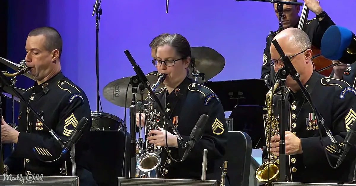 A military band member plays saxophone in a uniformed ensemble with other musicians.