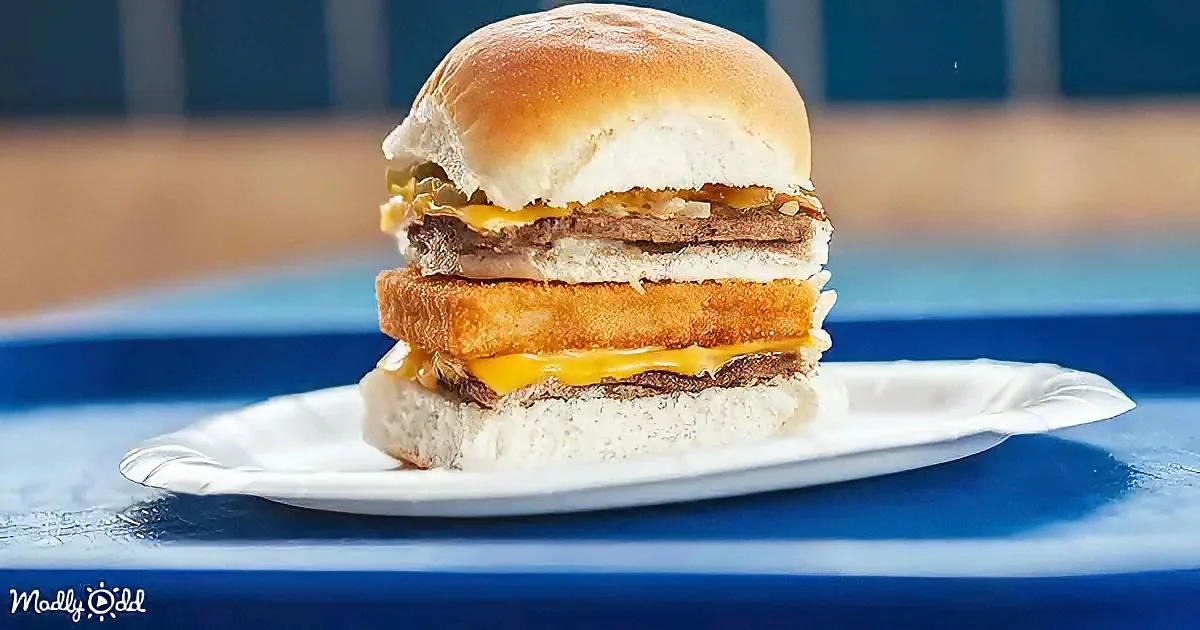 A burger with a fried chicken patty, cheese, and meat on a white plate.