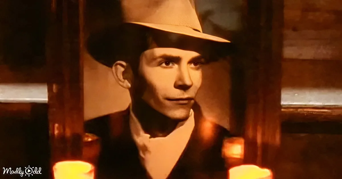 A man in a fedora and suit stands in a dimly lit room with candles, creating a dramatic atmosphere.