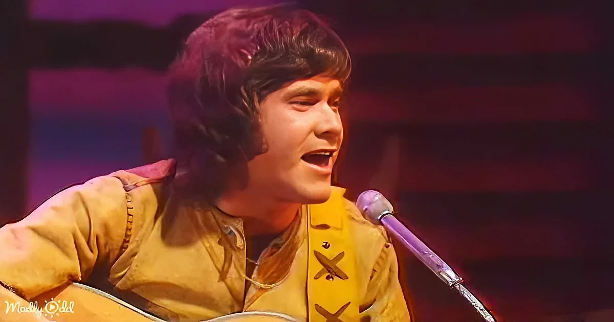 A person in a yellow shirt sings into a microphone while holding a guitar.