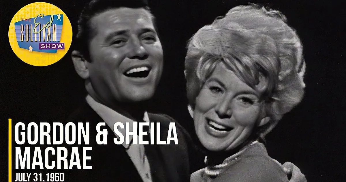 A man and woman are singing together, both with expressive faces, in a black-and-white image.