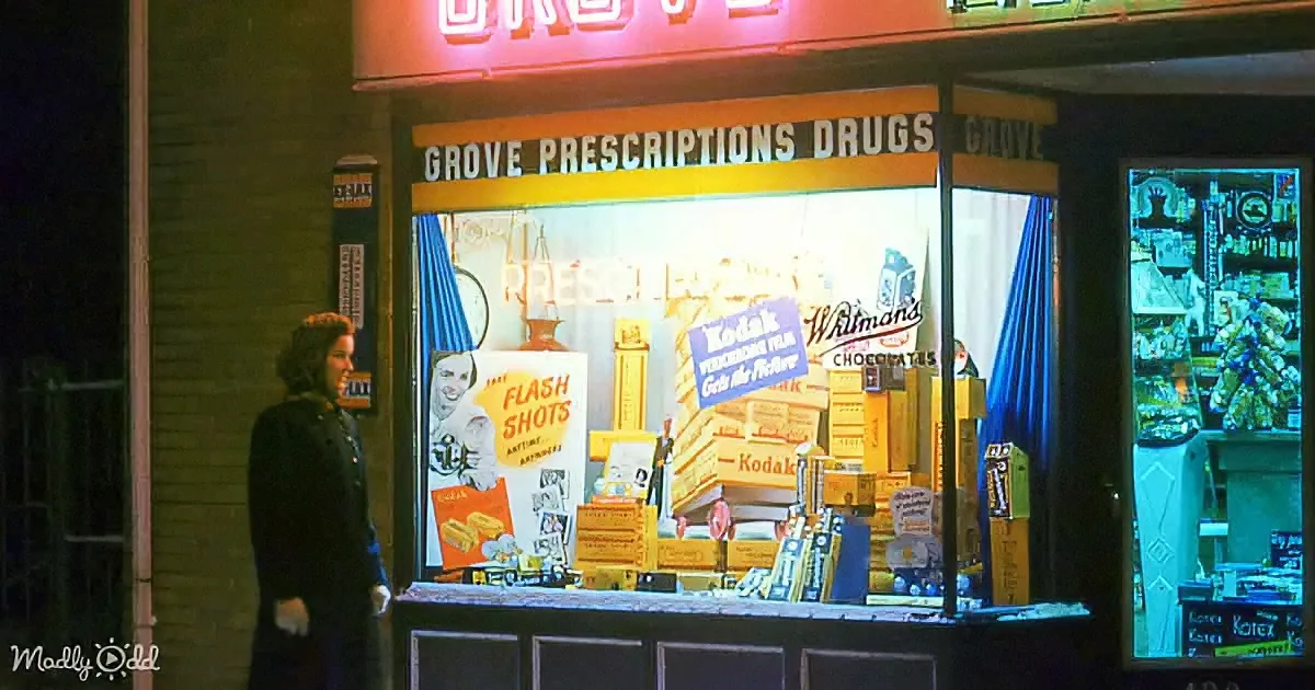 A woman stands outside a brightly lit "Grove Prescriptions Drugs" store window displaying vintage advertisements.