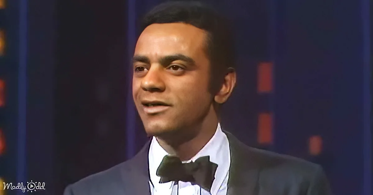 A man in a tuxedo with a bow tie smiles while wearing a white shirt and dark suit.