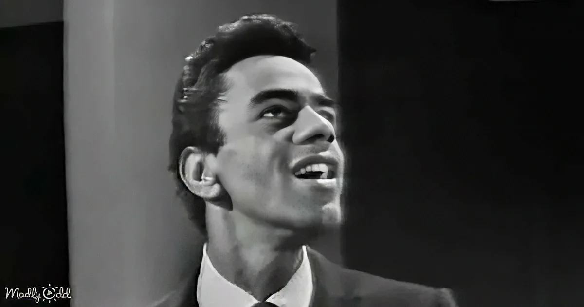 A man in a suit and tie looks upward, mouth slightly open, in a black-and-white image.