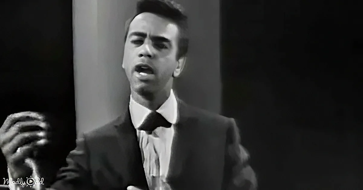 A man in a suit and tie is singing passionately, captured in a black-and-white image.
