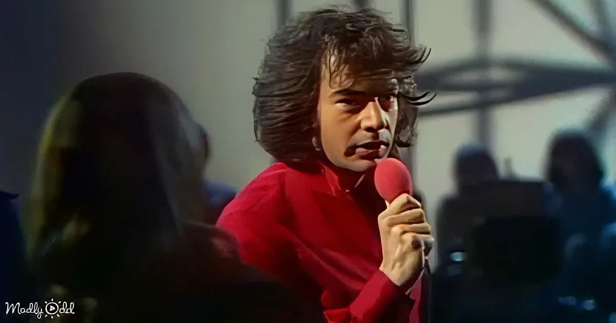 A person in a red shirt holds a microphone, singing passionately in front of an audience.