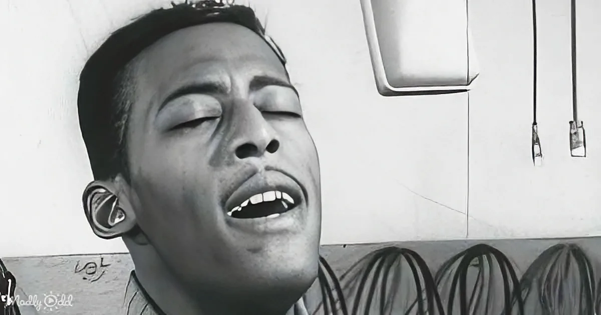 A person with eyes closed, mouth open, and a tattoo visible on their ear.