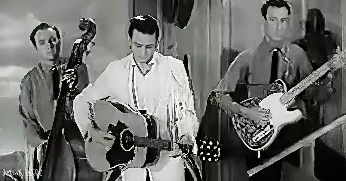 A man in a white shirt plays guitar while two others, one with a cello and another with a guitar, stand nearby.