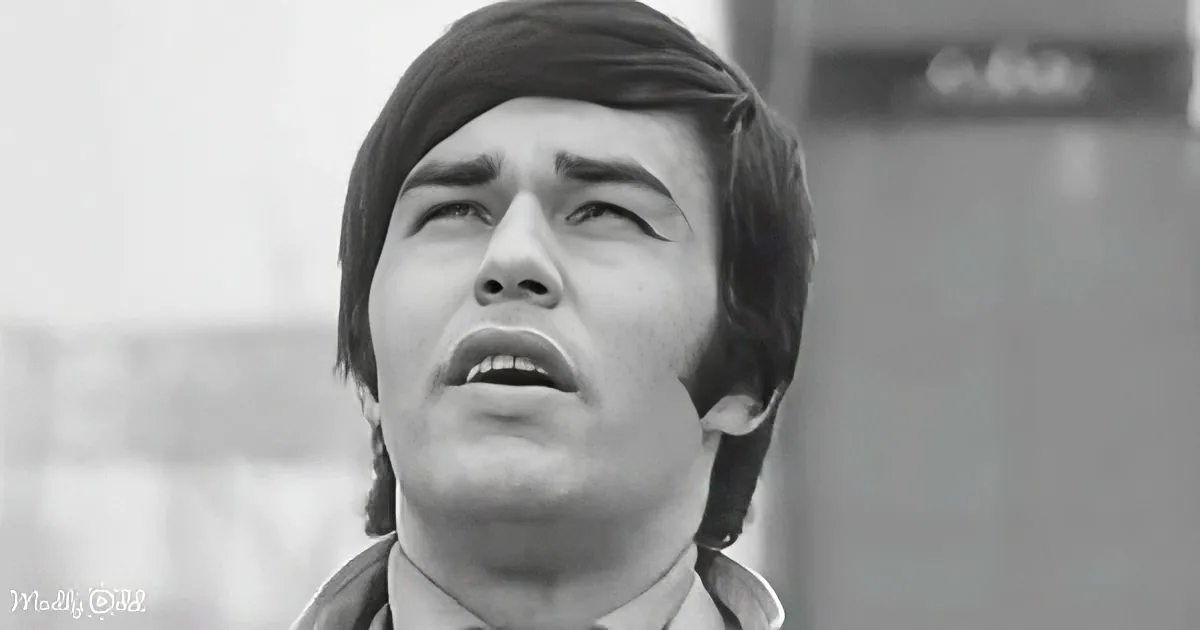 A man with short, dark hair and a surprised expression, mouth slightly open, looking upwards.