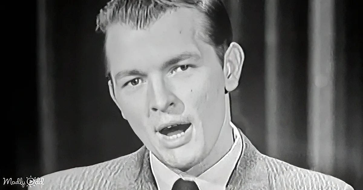 A man in a suit and tie, mid-speech, with a serious expression, in a black-and-white image.