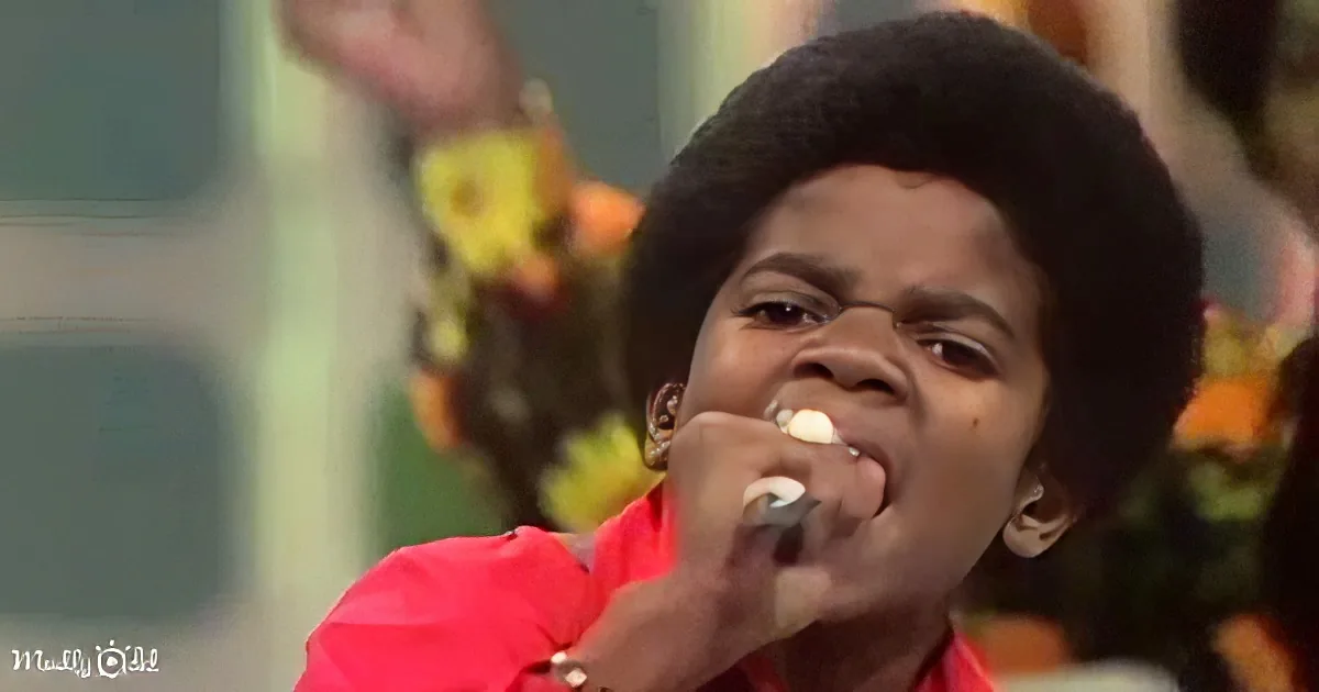 A young person in a red shirt holds a microphone, singing passionately.