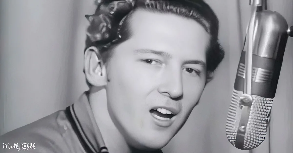 A man in a recording studio, wearing a hat, singing into a microphone.