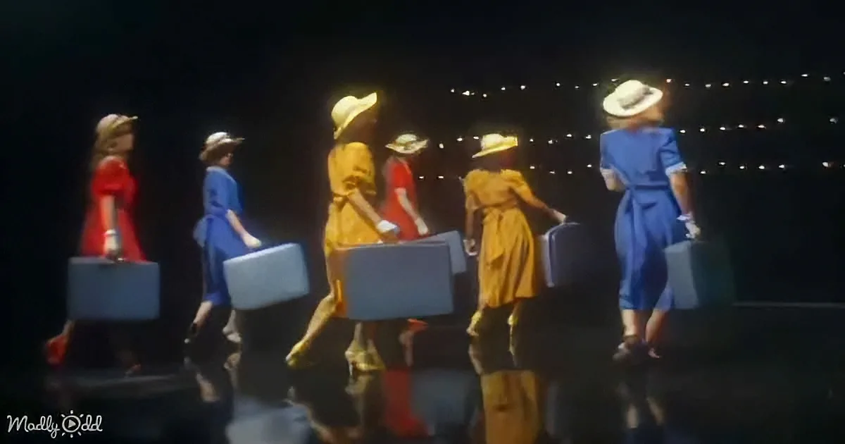 Women in vintage attire carry suitcases, walking in a line against a dark background with lights.