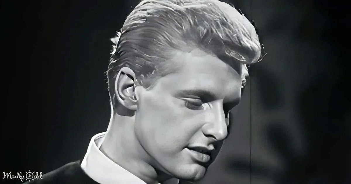 A man with short, styled hair and a white shirt is shown in a close-up, looking downward.