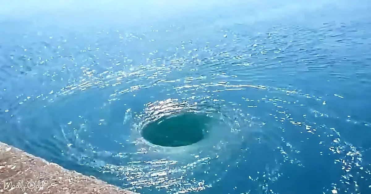 A swirling vortex in the ocean creates a mesmerizing circular pattern on the water's surface.