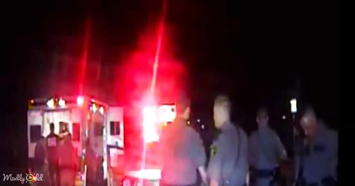 Ambulance with flashing red lights and emergency personnel at night.
