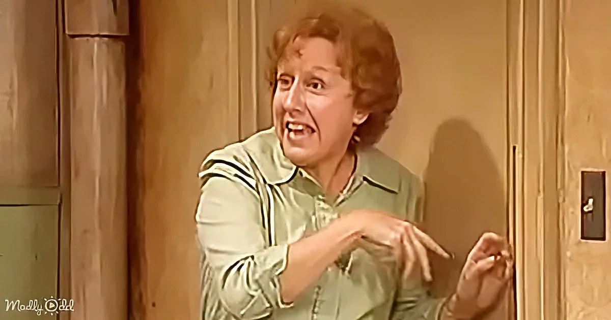 A woman in a green shirt is gesturing with her hands, appearing to speak or explain something.