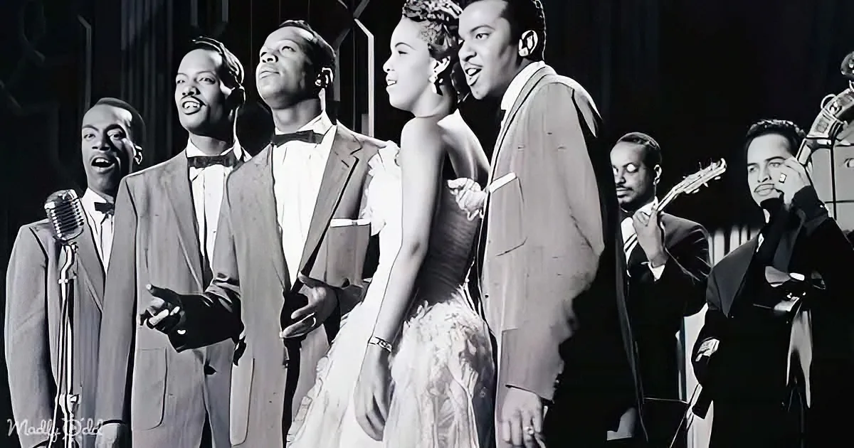A group of performers in formal attire sing and play instruments on stage.