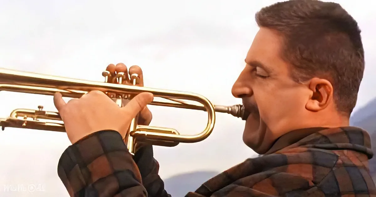 A man in a plaid shirt plays a trumpet with his eyes closed, set against a blurred background.