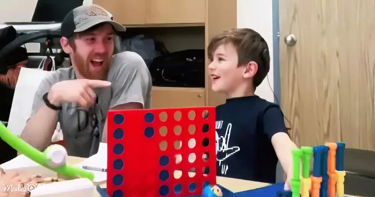 A man and a boy are excitedly playing with colorful building blocks and a red grid game.