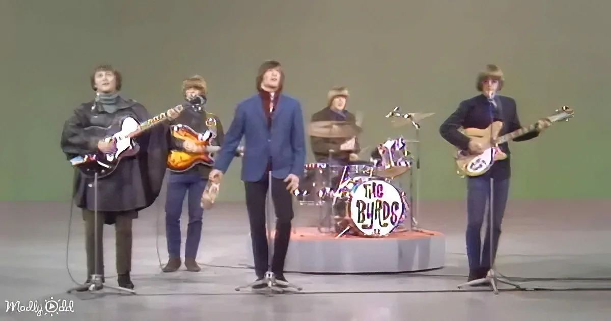 The Byrds perform on stage with guitars, drums, and microphones.