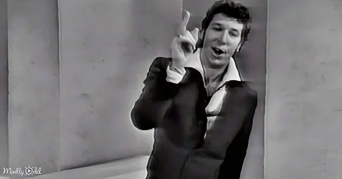 A man in a suit and tie makes a peace sign with his hand.