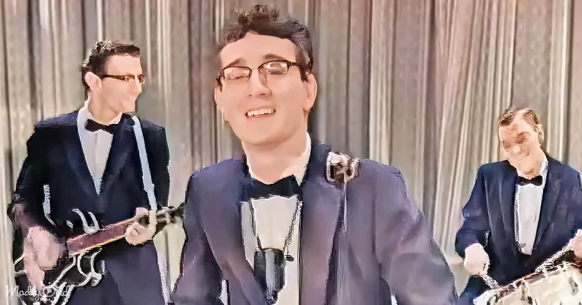 A man in a suit and bow tie smiles, surrounded by two musicians playing banjos.