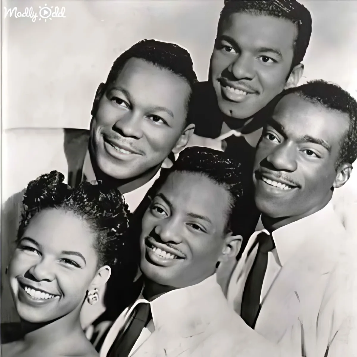 A group of smiling individuals, dressed in suits and ties, posing together in a vintage black-and-white photo.