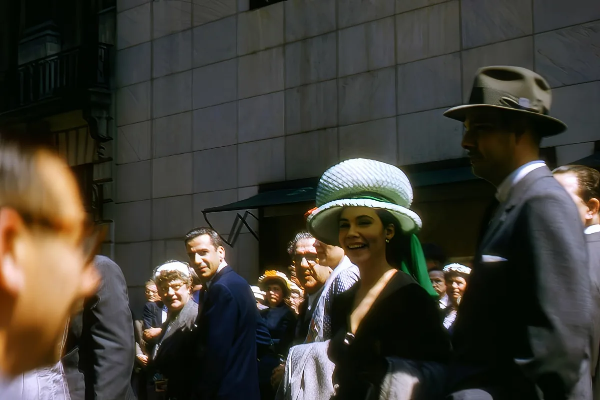 A man in a suit and hat is surrounded by a crowd of people in formal attire, possibly at a historical event.