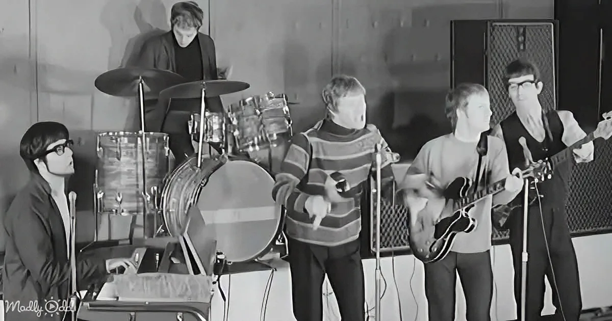 A band performs with a drummer, guitarists, and keyboardist in a vintage setting.