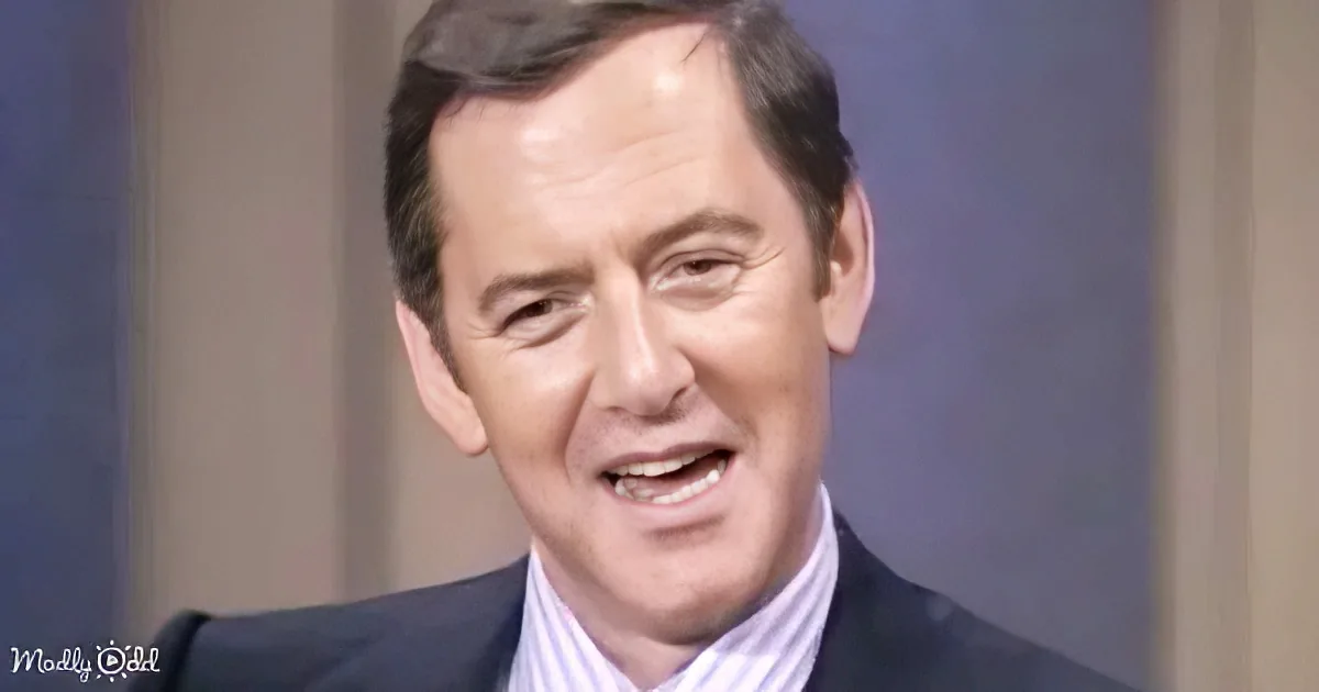 A man in a suit and striped shirt is speaking, with a blurred background.