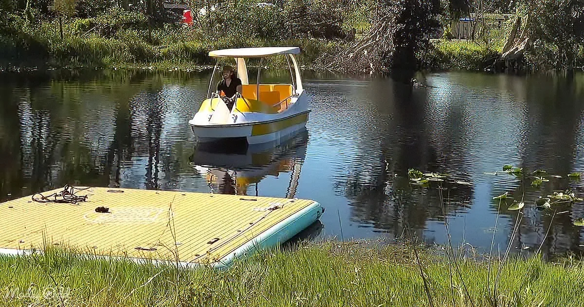 A person in a small yellow and white boat on a calm river surrounded by greenery.