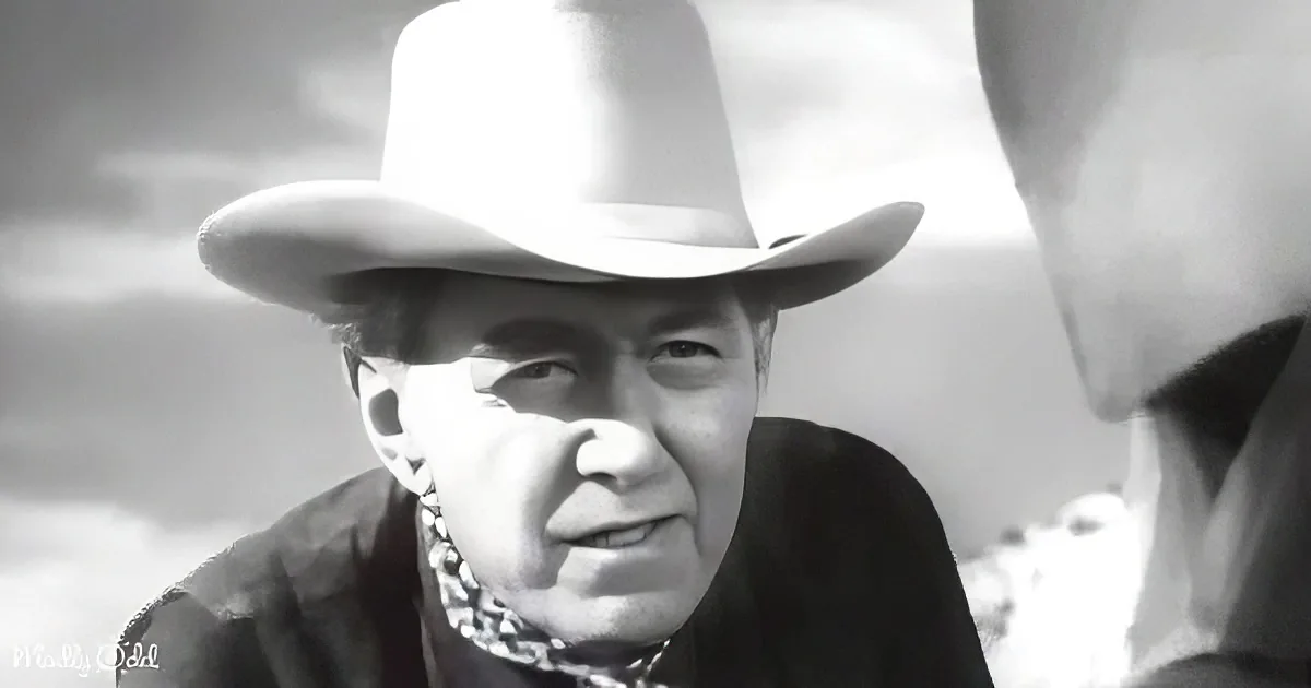 A man in a cowboy hat and bandana, looking to the side, in a black-and-white image.