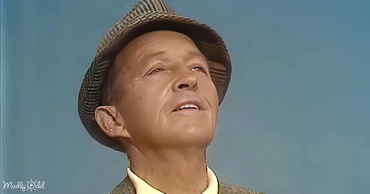 A man wearing a striped hat and a yellow shirt looks upward with a slight smile.