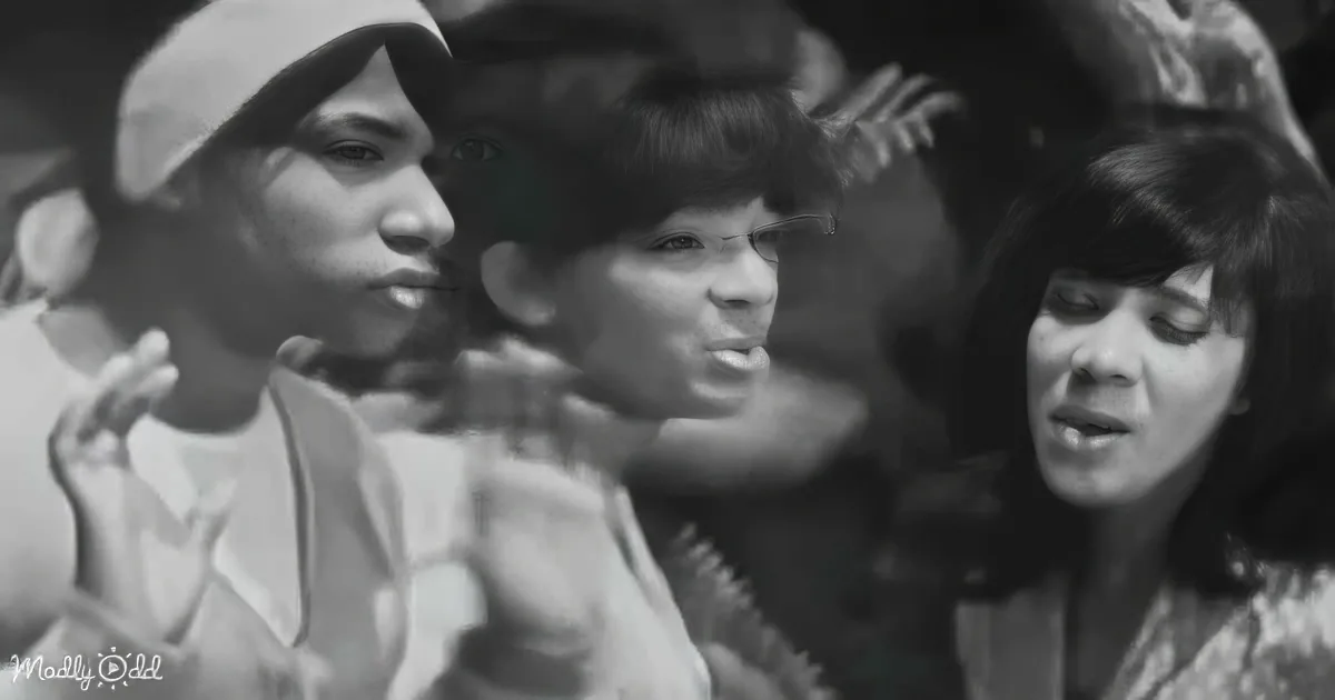 A woman in a baseball cap gestures while another woman in a floral dress looks on, both in a crowd.