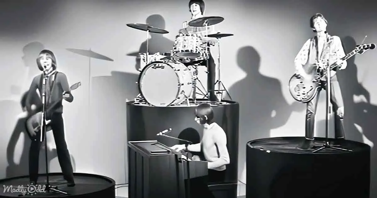 Four Beatles figures in black and white, playing instruments on stage.