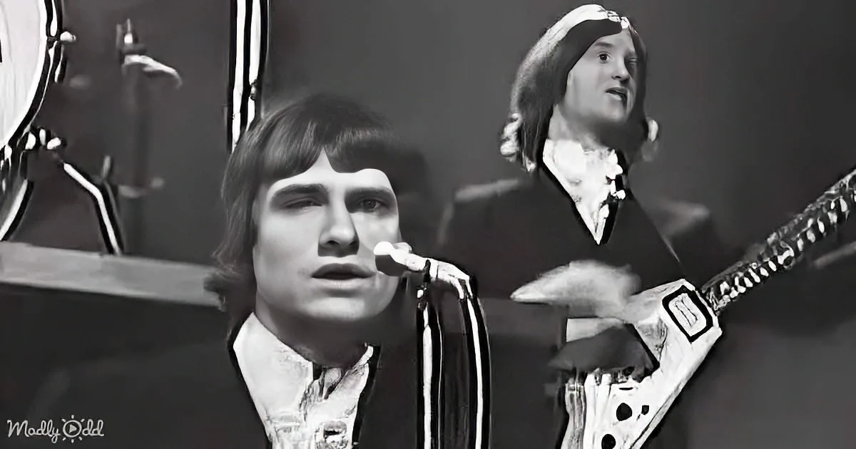 A musician sings into a microphone, another plays guitar, both in a band setting.