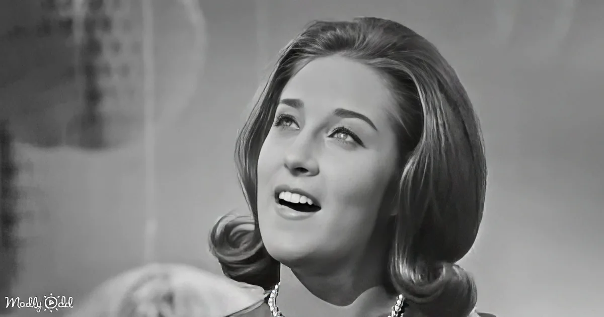 A woman with shoulder-length hair, wearing a necklace, smiles upward in a black-and-white image.