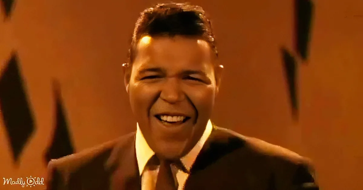 A smiling man in a suit and tie, with a warm, orange-toned background.